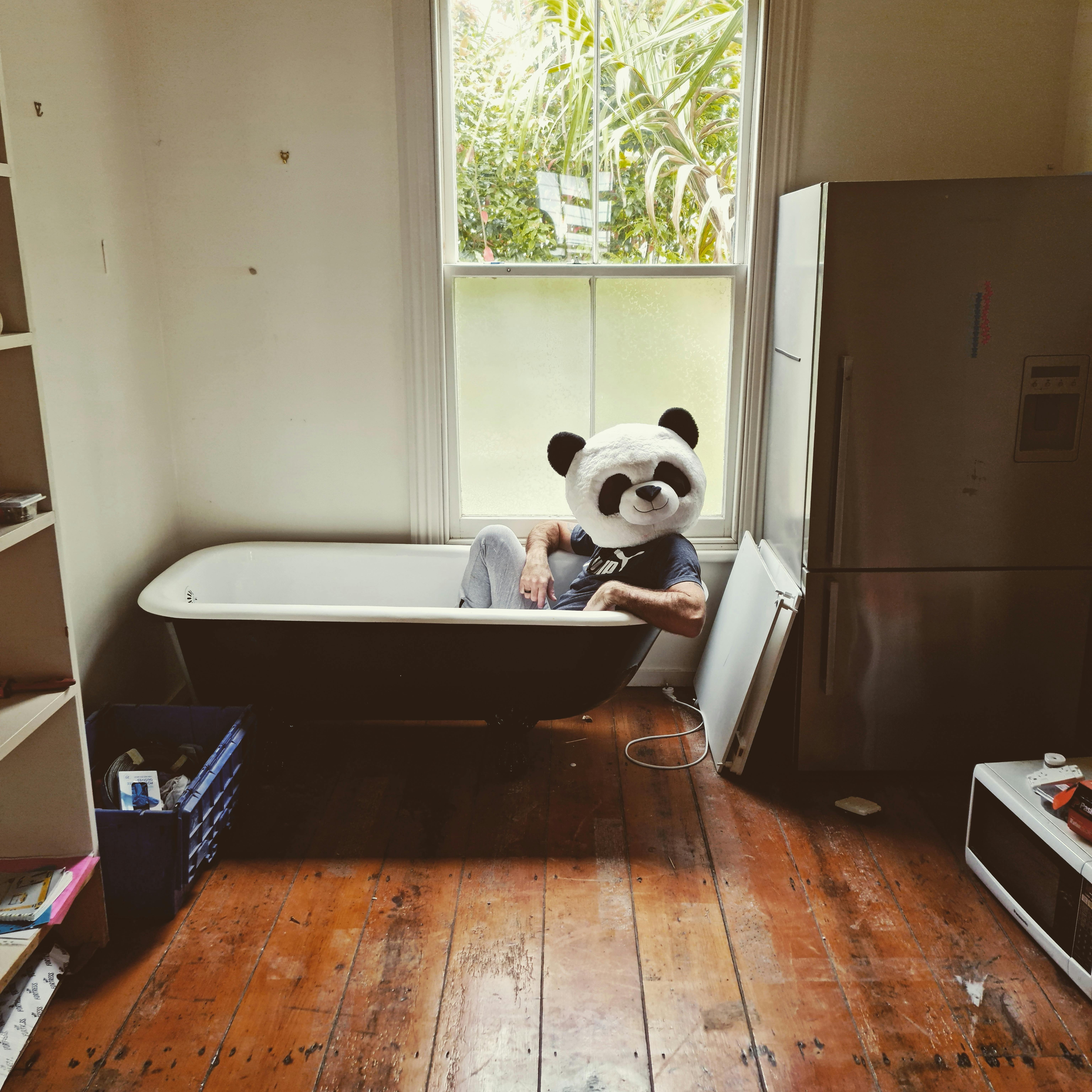 Playful scene with a person in a panda costume in a bathtub indoors.